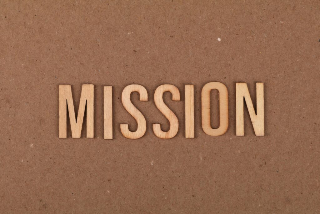 Wooden letters spelling 'MISSION' on textured cardboard background, emphasizing goals and purpose.