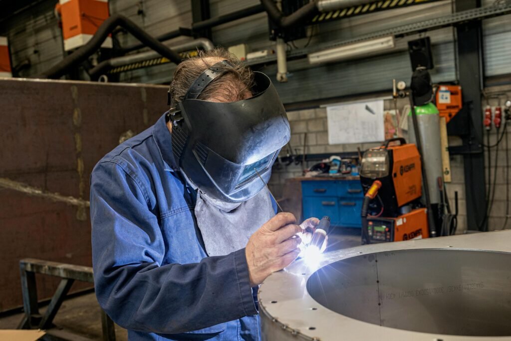 A skilled welder working in a modern workshop with advanced equipment and safety gear.