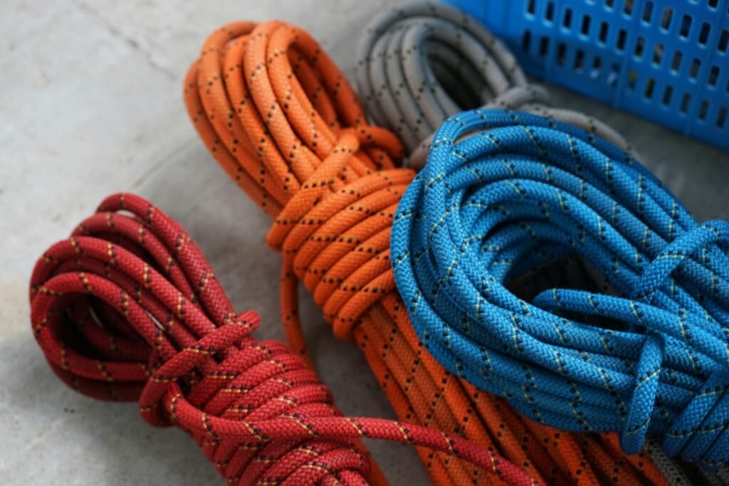 Vibrant red, orange, and blue climbing ropes coiled on concrete surface.