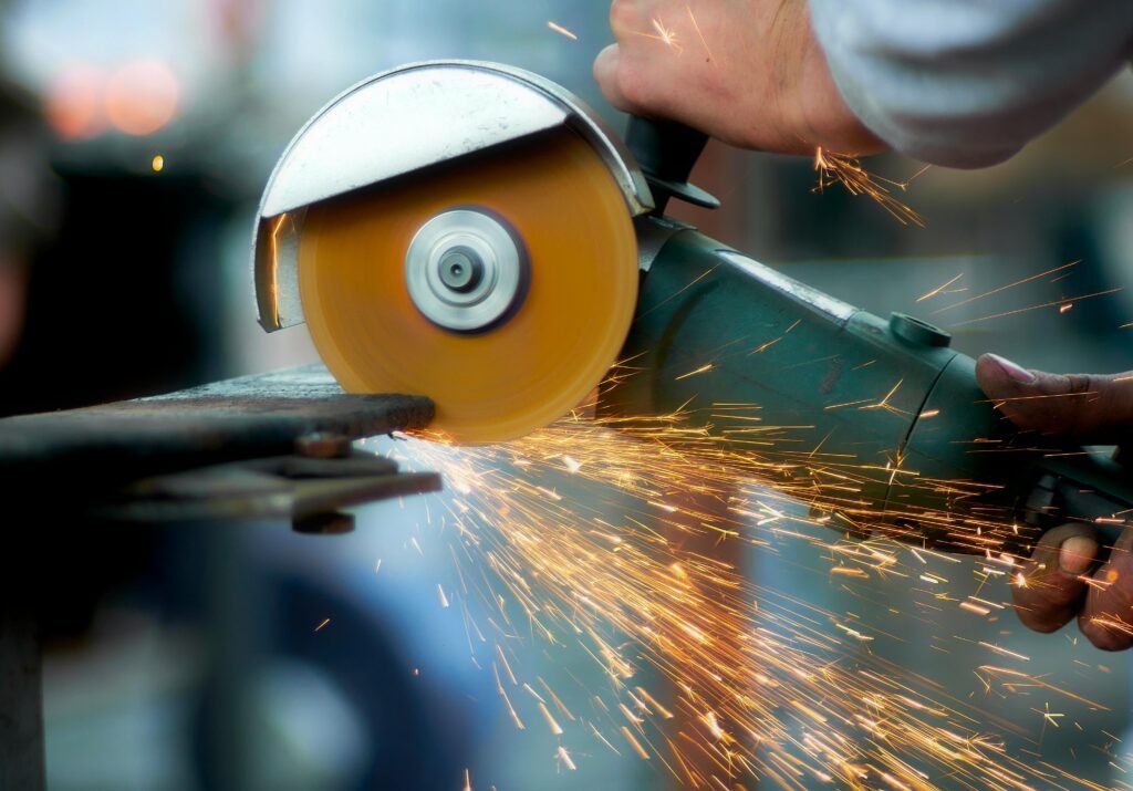 Angle grinder creating sparks on metal in a workshop.