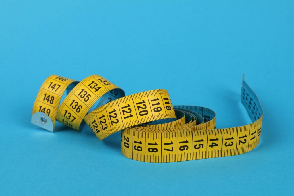 A vibrant close-up of a coiled yellow and blue measuring tape on a blue background.