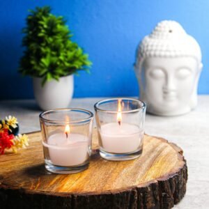 Candles on a wooden tray with a Buddha sculpture and plant, promoting tranquility and meditation.