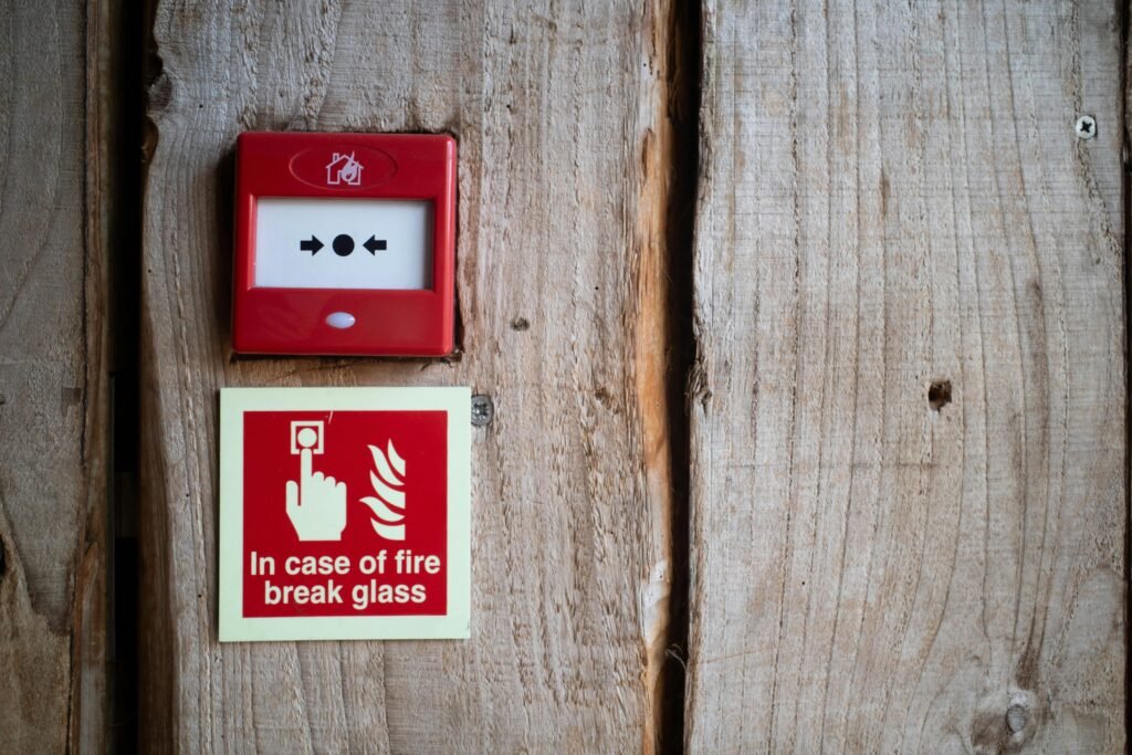 Red fire alarm and warning sign on a rustic wooden wall for safety awareness indoors.