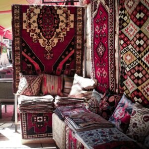 A vibrant display of traditional Middle Eastern rugs and textiles in a market setting, showcasing intricate patterns.