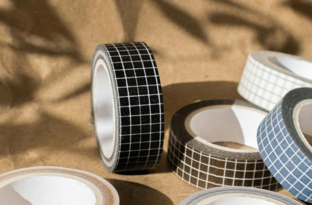 A collection of decorative washi tape rolls with grid patterns on a brown craft paper background in natural lighting.
