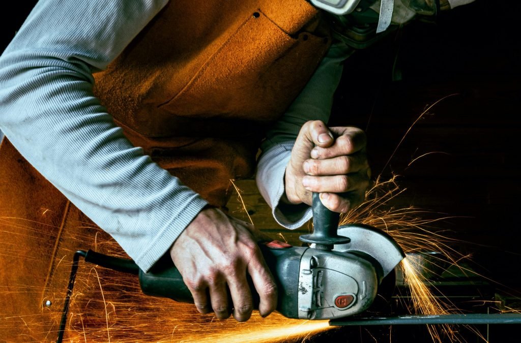 A craftsman using an angle grinder in a workshop, creating vibrant sparks.