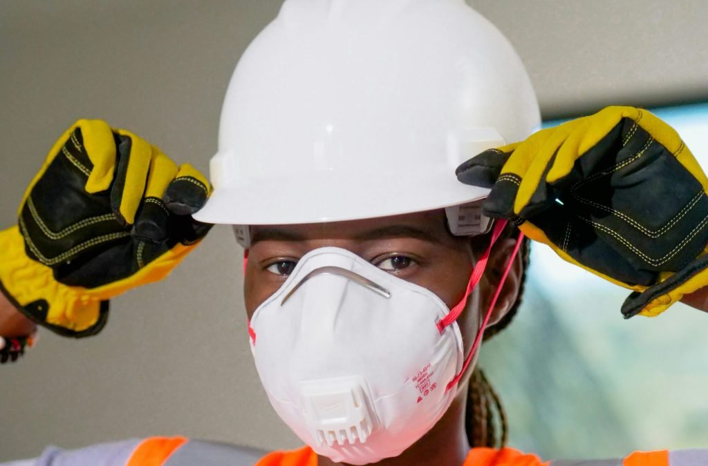 Construction worker wearing hardhat, N95 mask, and gloves for safety.